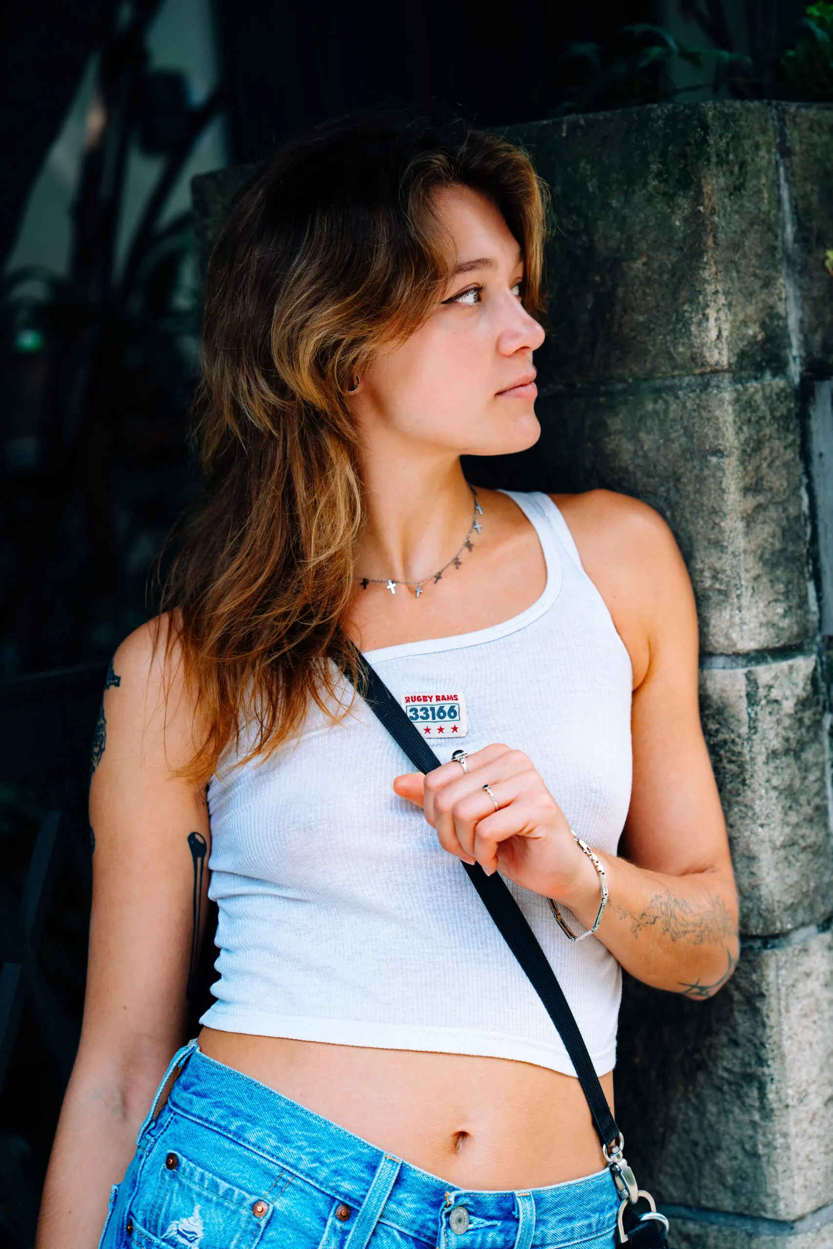Woman in a white top leaning against a tree