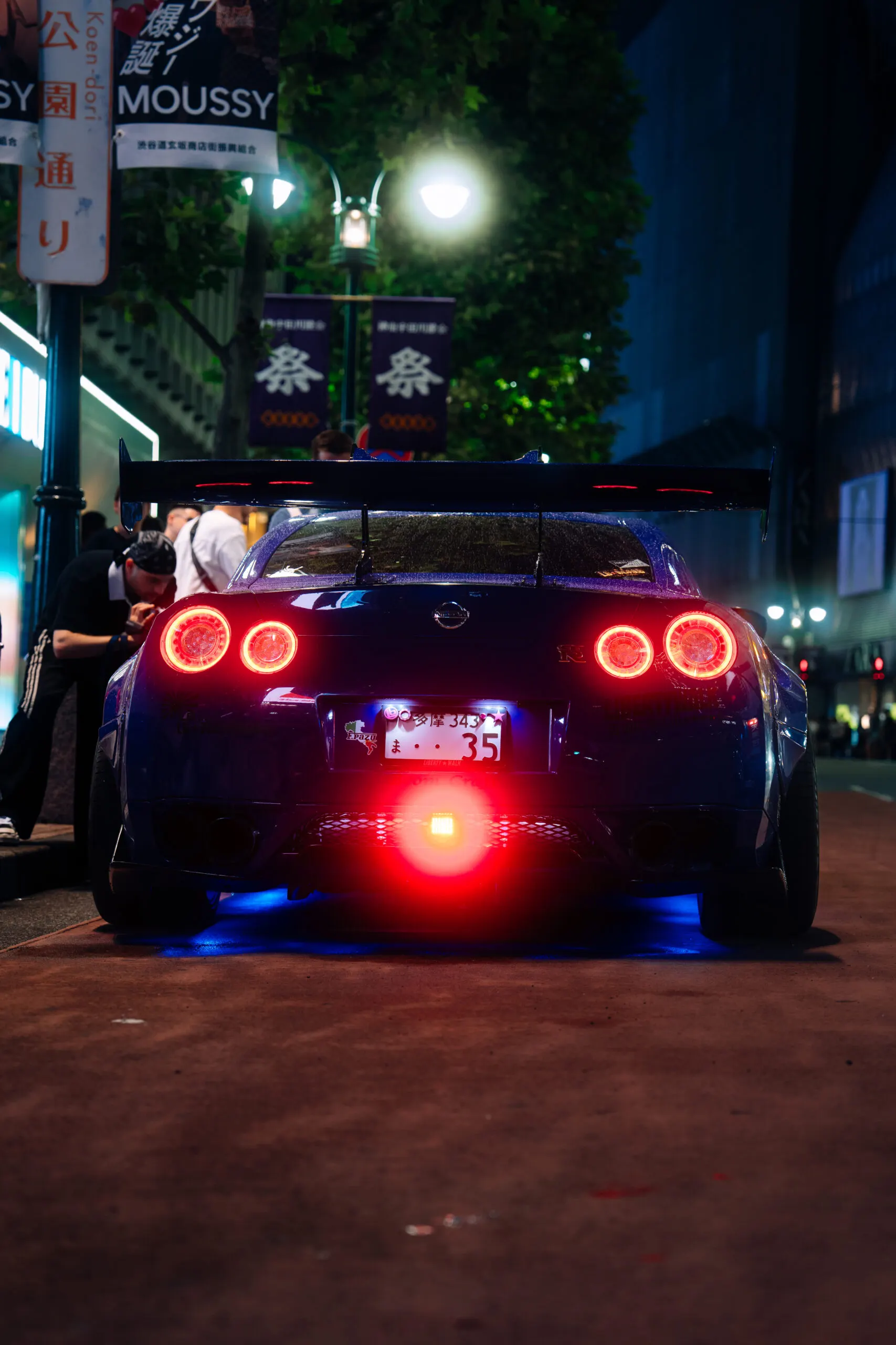 Rear view of a dark GT-R with red tail lights at night