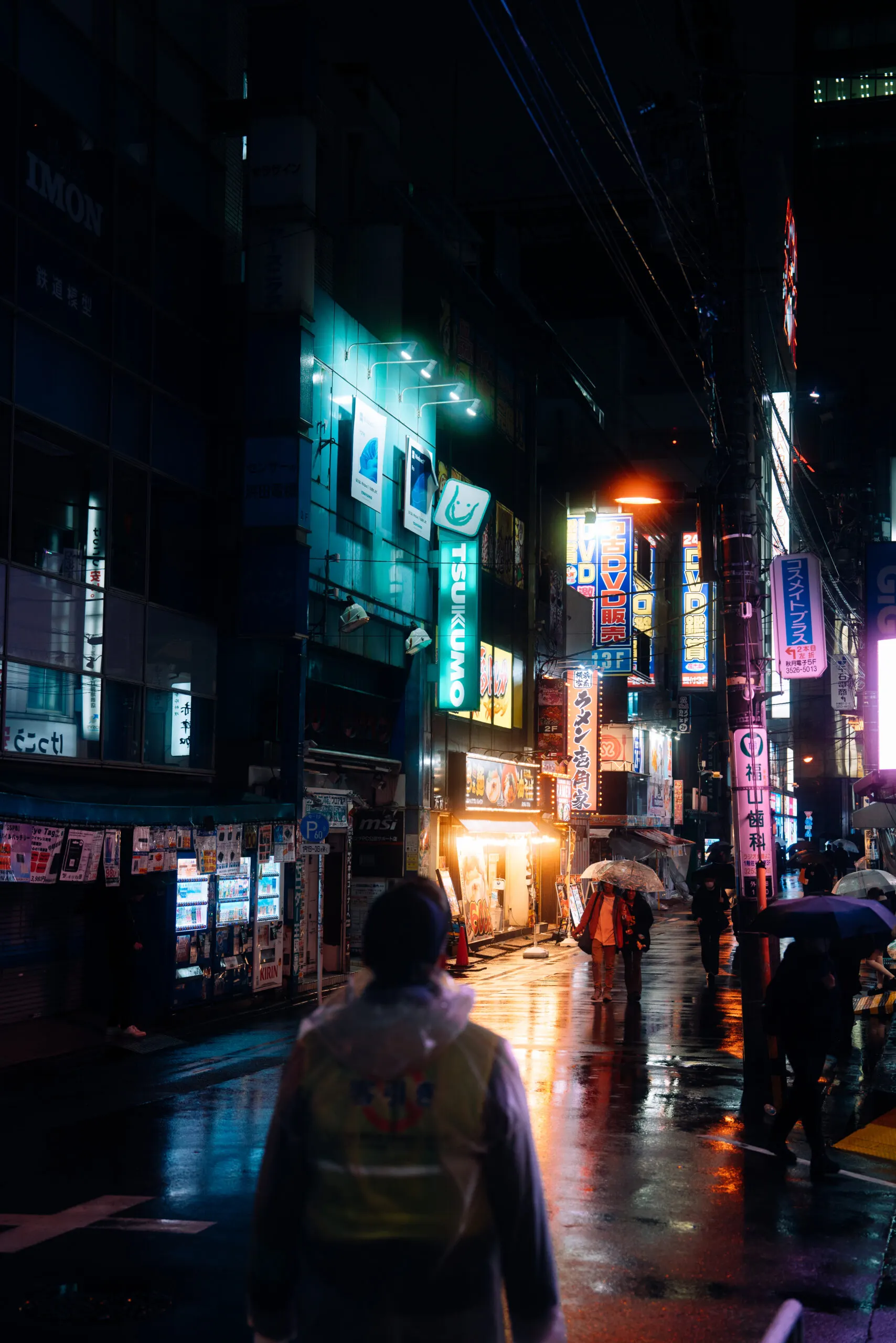 Person walking through a wet neon-lit alley